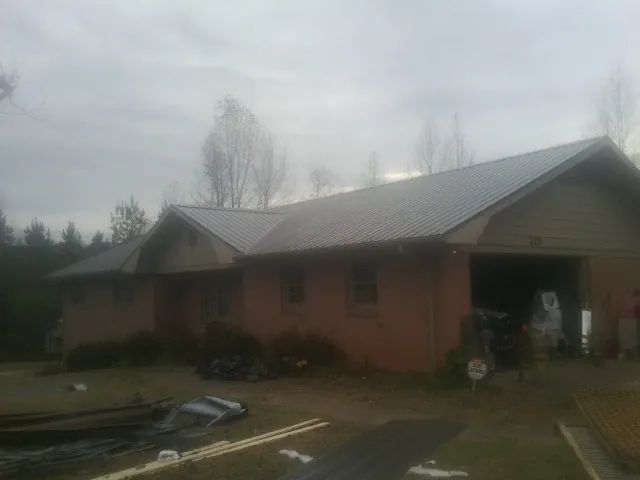 Gray metal roof on a stucco house with an attached garage in Brookville