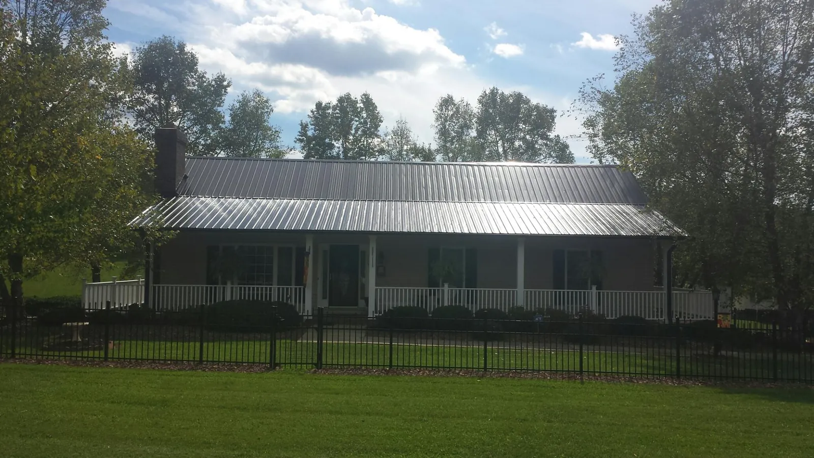 Gray metal roof on a brick ranch with a full width front porch — Gutter Guard Installation work by our crew in Brookville