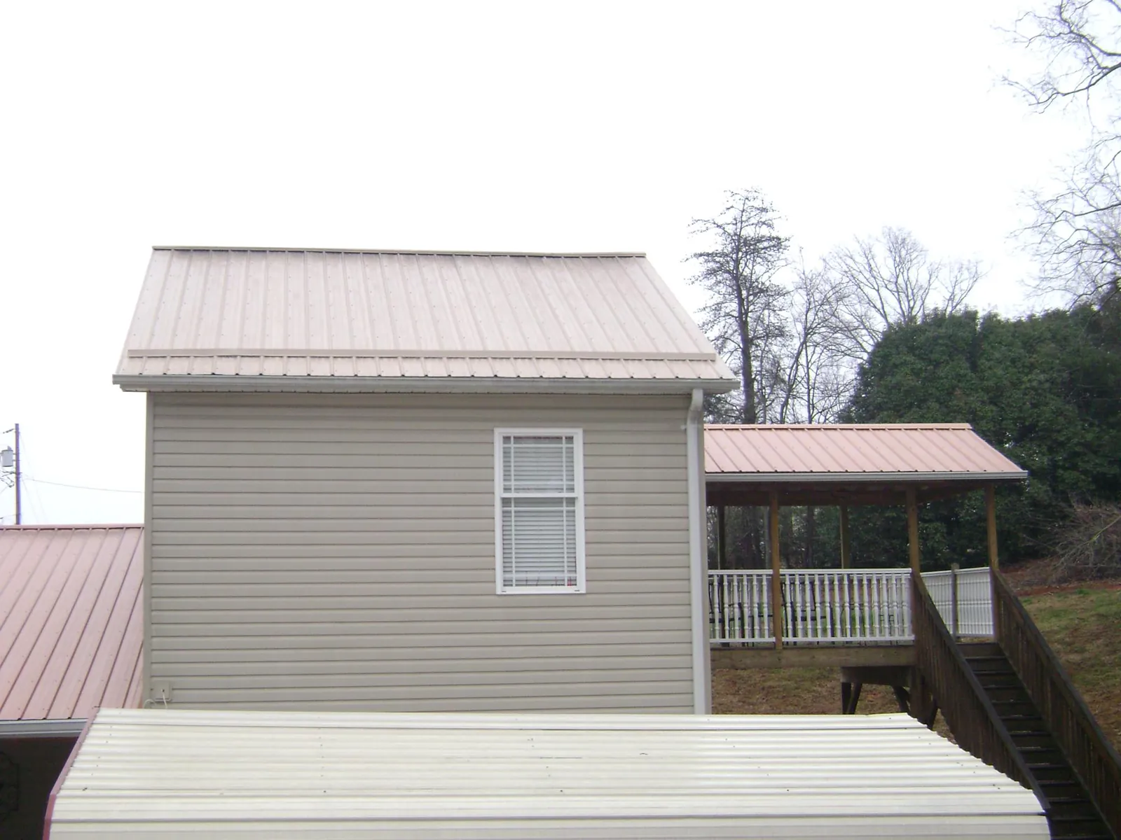 Tan metal roofs on a two story addition and attached porch, from a Roof Replacement job in Brookville